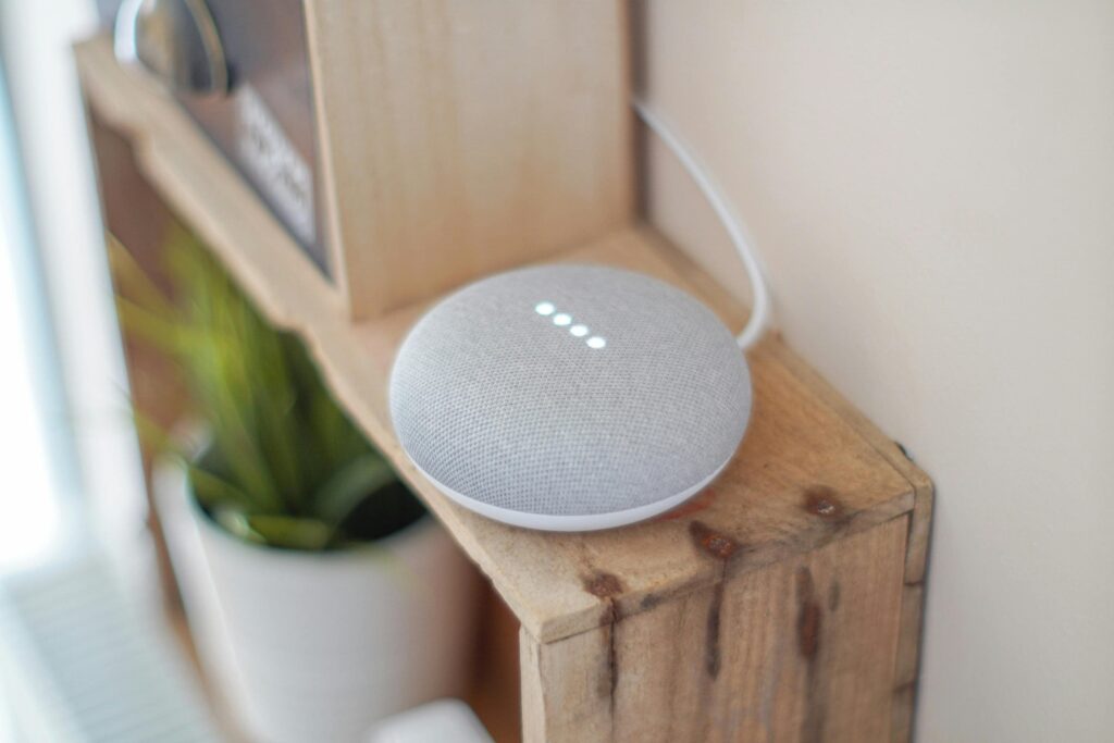 Enceinte connectée intelligente placée sur un meuble en bois près d'une plante d'intérieur. Symbole d'une maison moderne avec l'adoption des technologies de l'IA.